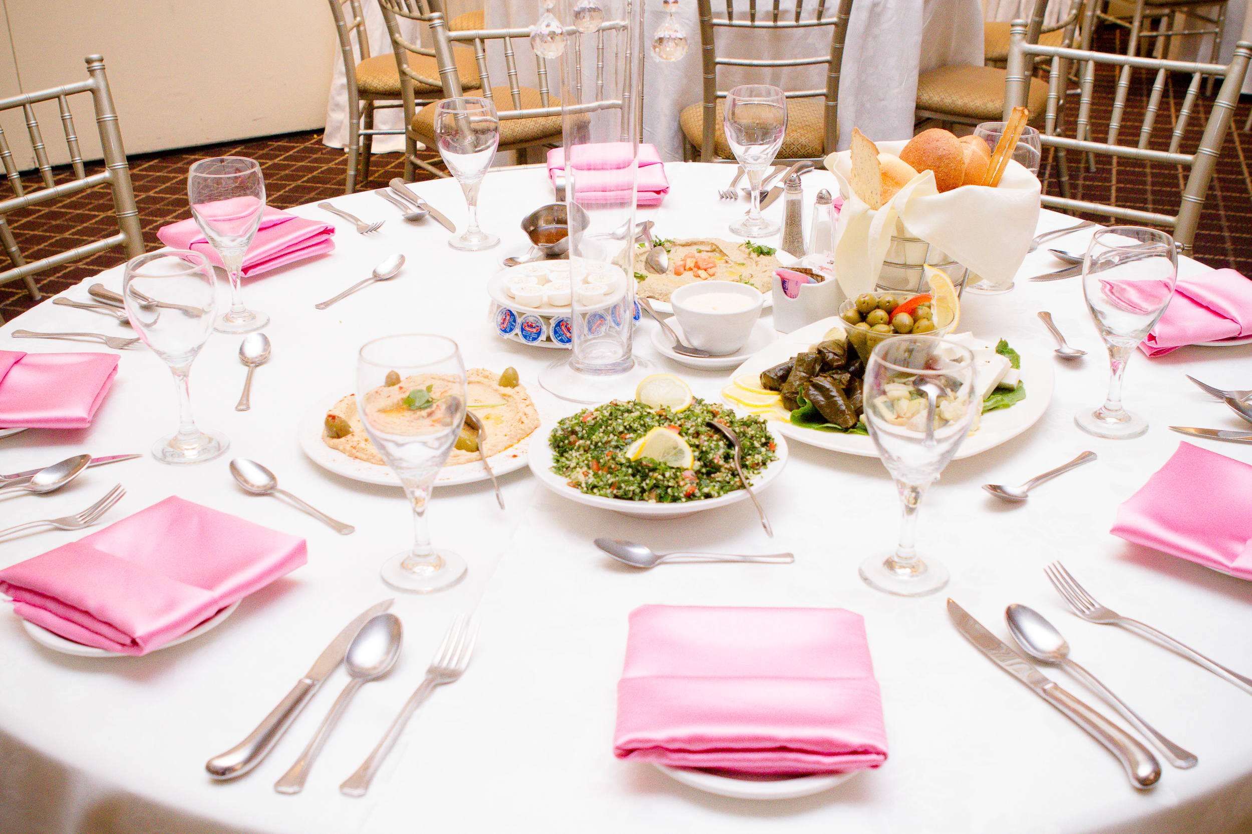 Wedding reception table setup with pink napkins, floral decor, and plated dishes