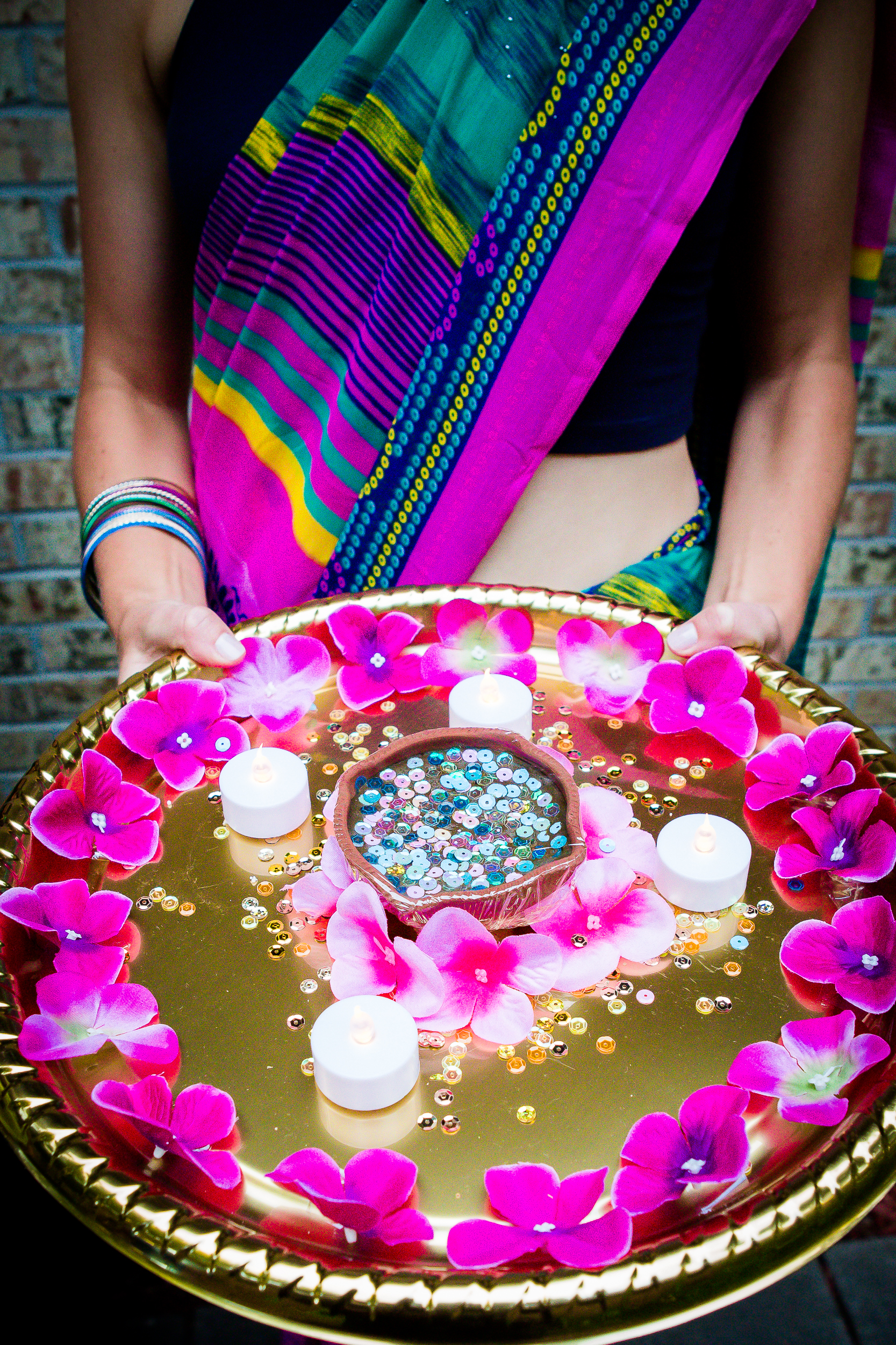 Woman in traditional attire holding a decorated ceremonial tray at a wedding event