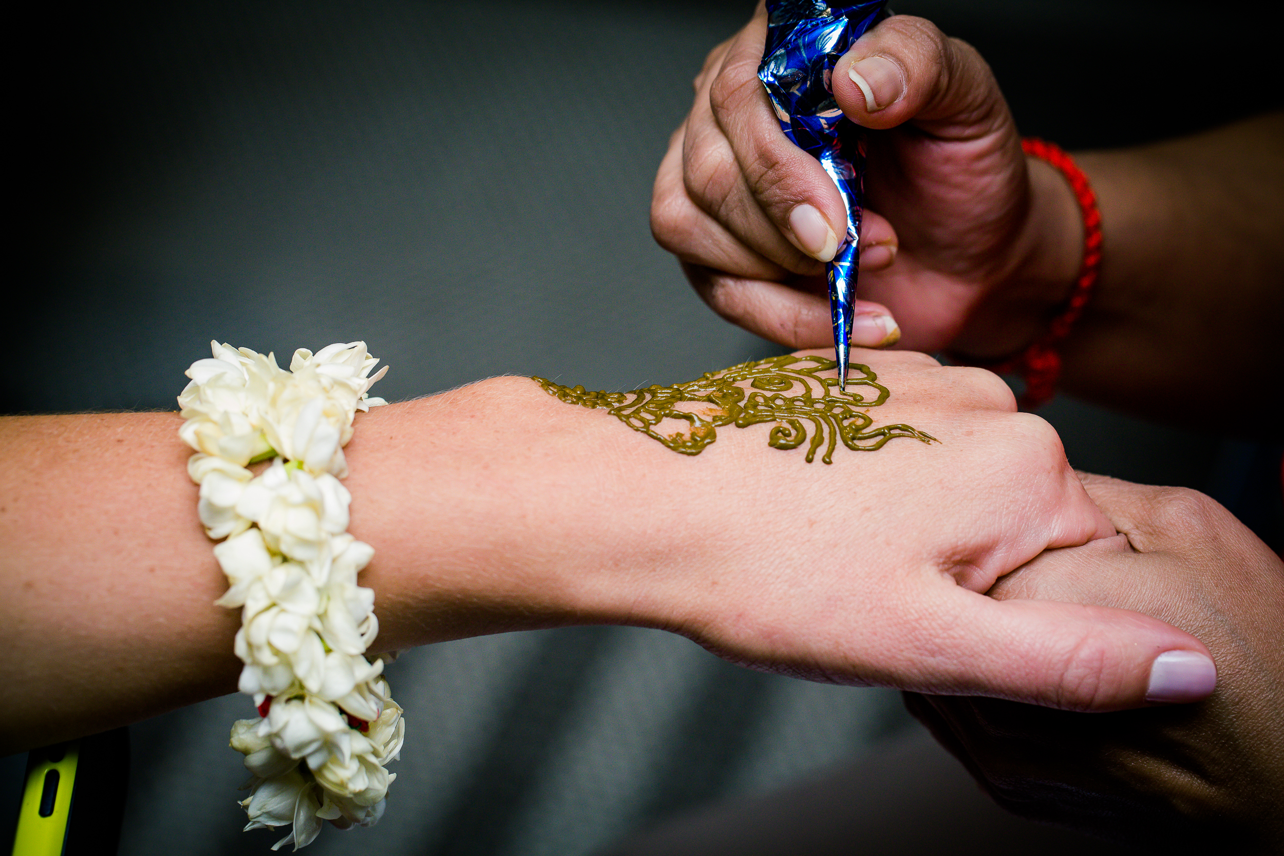 Henna artist applying mehndi design on a guest's hand during a wedding celebration